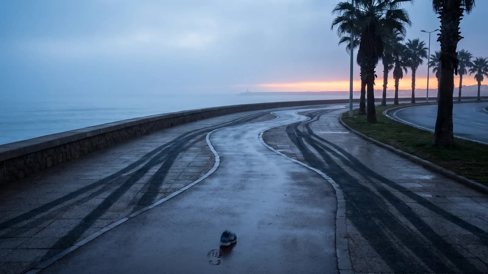 Promenade littorale déserte à l’aube au Maroc, palmiers et brume sur l’Atlantique