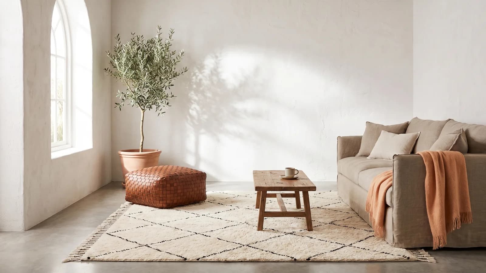 Salon marocain contemporain baigné de lumière matinale : tapis Beni Ourain, pouf tressé, olivier en pot