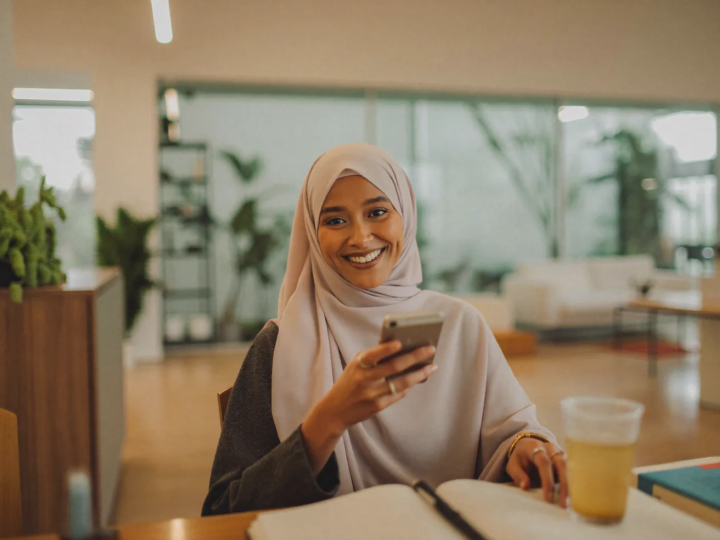 Une jeune femme sourit, smartphone en main, dans un espace de coworking à Rabat